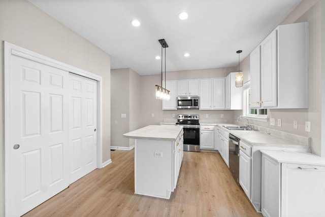 kitchen featuring white cabinetry, light wood-type flooring, a kitchen island, pendant lighting, and stainless steel appliances