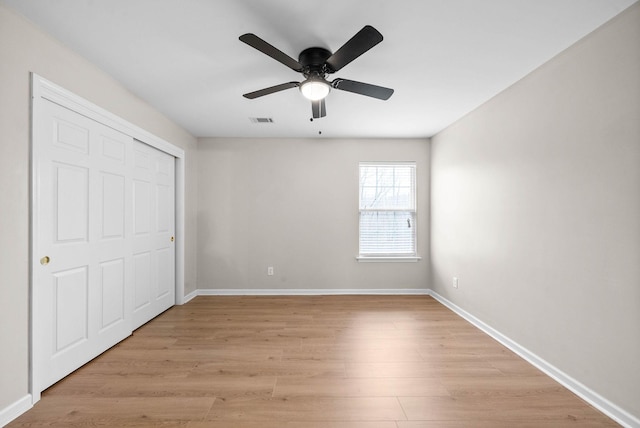 unfurnished bedroom featuring ceiling fan, light hardwood / wood-style floors, and a closet