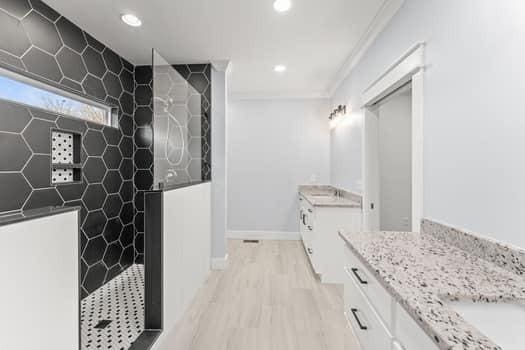 full bath featuring recessed lighting, wood finished floors, two vanities, baseboards, and walk in shower