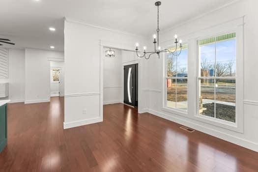 unfurnished dining area with a chandelier, recessed lighting, wood finished floors, visible vents, and baseboards