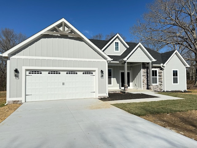 view of front of house featuring an attached garage, a shingled roof, driveway, stone siding, and board and batten siding