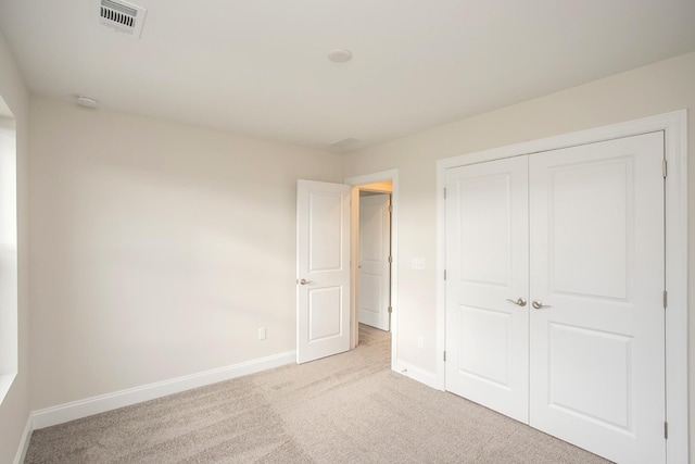 unfurnished bedroom featuring light colored carpet and a closet