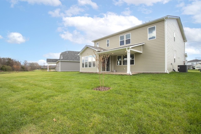 rear view of house with central AC and a yard