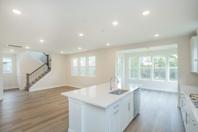 kitchen featuring dishwasher, sink, a center island with sink, and white cabinets