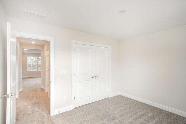 unfurnished bedroom featuring light carpet and a closet