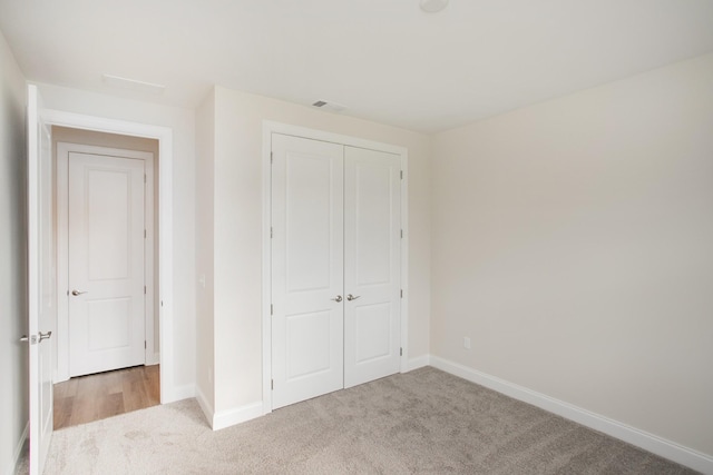 unfurnished bedroom with light carpet and a closet