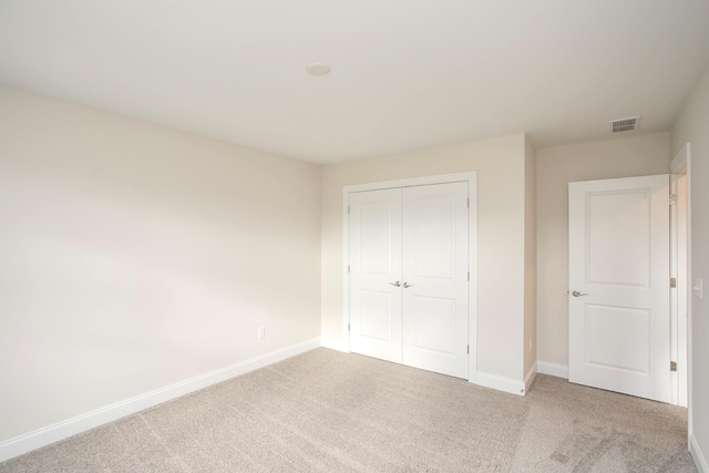 unfurnished bedroom featuring light colored carpet and a closet