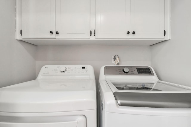 laundry room featuring separate washer and dryer and cabinets