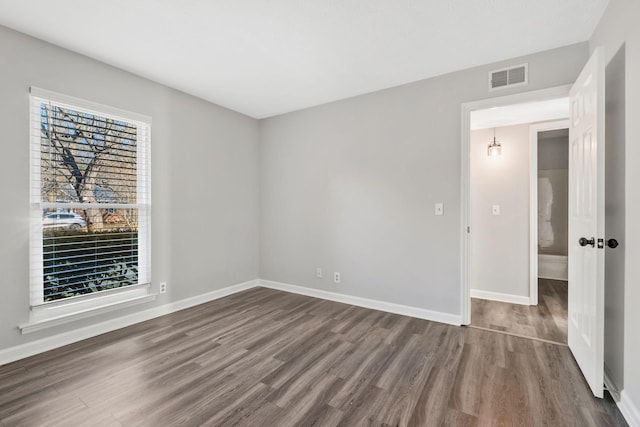 spare room featuring a wealth of natural light and dark hardwood / wood-style flooring