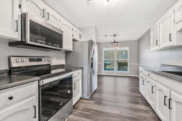 kitchen featuring pendant lighting, dark wood-type flooring, stainless steel appliances, a textured ceiling, and white cabinets