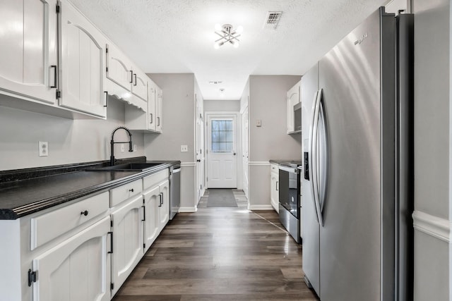 kitchen with dark hardwood / wood-style flooring, sink, stainless steel appliances, and white cabinets