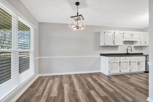 kitchen with pendant lighting, sink, light hardwood / wood-style flooring, white cabinetry, and a chandelier