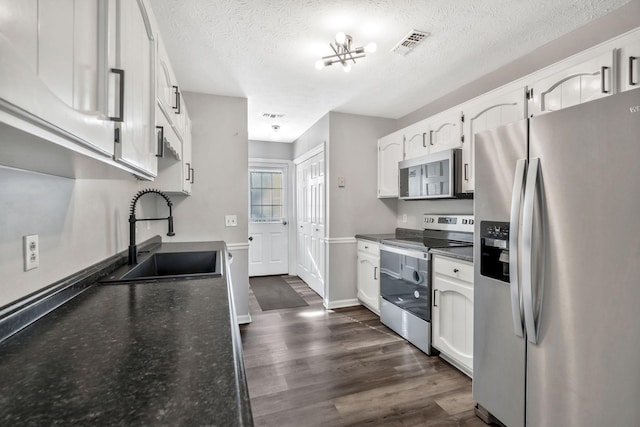 kitchen with white cabinetry, sink, stainless steel appliances, dark wood-type flooring, and a textured ceiling