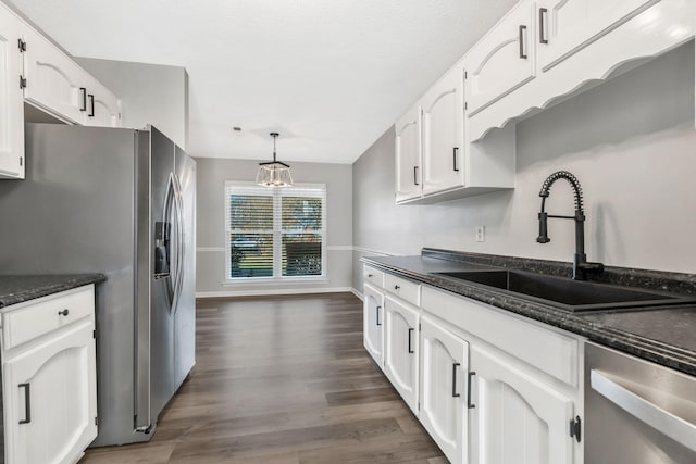 kitchen with hanging light fixtures, appliances with stainless steel finishes, sink, and white cabinets