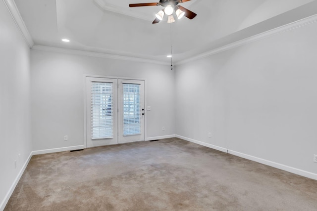 carpeted spare room with ceiling fan, ornamental molding, and a raised ceiling