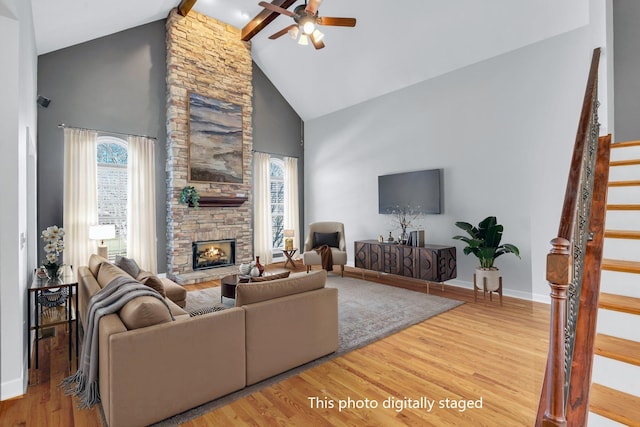 living room featuring hardwood / wood-style floors, a fireplace, high vaulted ceiling, ceiling fan, and beam ceiling