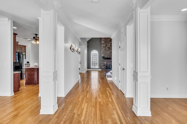 hall with crown molding, decorative columns, and light hardwood / wood-style floors