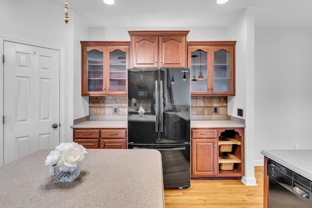 kitchen with backsplash, light hardwood / wood-style floors, and black appliances