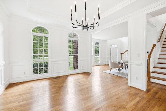 unfurnished dining area with a raised ceiling, crown molding, a chandelier, and light hardwood / wood-style floors