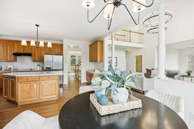 kitchen featuring hardwood / wood-style flooring, an inviting chandelier, a center island, stainless steel refrigerator with ice dispenser, and tasteful backsplash