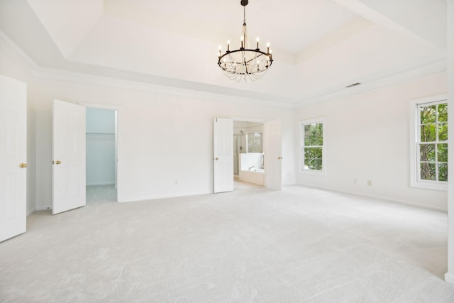 interior space with a wealth of natural light, ornamental molding, light colored carpet, and a tray ceiling