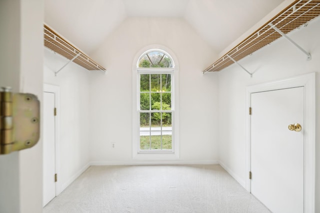 interior space featuring lofted ceiling and light carpet