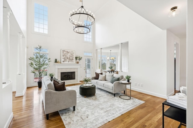 living room featuring a fireplace, a chandelier, light hardwood / wood-style flooring, and ornate columns