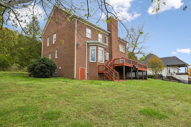 rear view of house featuring a wooden deck and a lawn