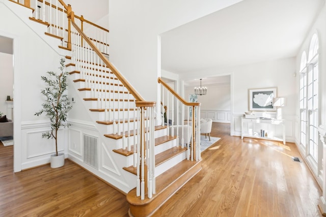 staircase featuring wood-type flooring and a notable chandelier