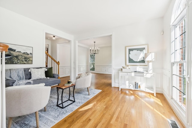 living room featuring plenty of natural light, light hardwood / wood-style flooring, and a notable chandelier