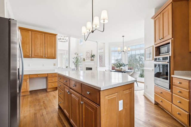 kitchen with a chandelier, hanging light fixtures, light hardwood / wood-style flooring, a kitchen island, and stainless steel appliances