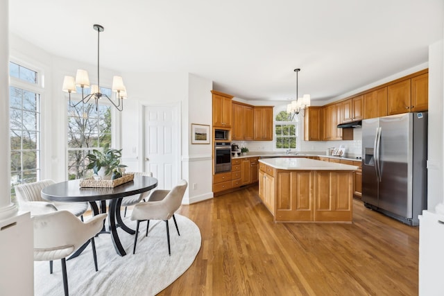 kitchen featuring light hardwood / wood-style flooring, hanging light fixtures, stainless steel appliances, a center island, and a notable chandelier