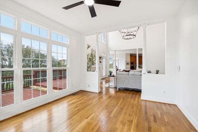 unfurnished sunroom with ceiling fan with notable chandelier