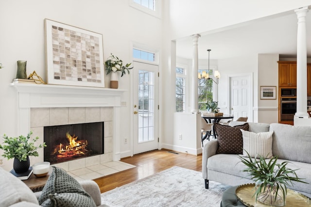 living room featuring ornate columns, plenty of natural light, a fireplace, and light hardwood / wood-style flooring