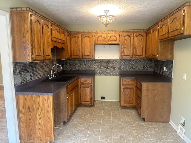 kitchen with sink, a textured ceiling, and backsplash