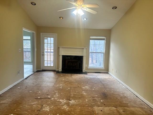 unfurnished living room featuring ceiling fan, plenty of natural light, lofted ceiling, and a fireplace