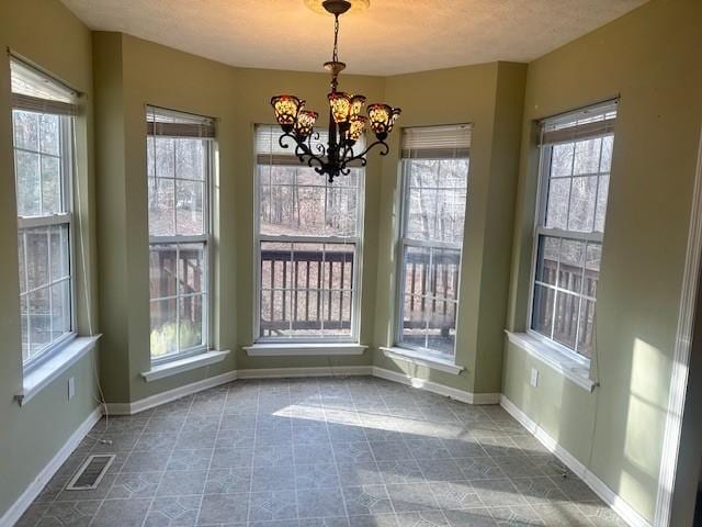 unfurnished dining area featuring a notable chandelier and a textured ceiling