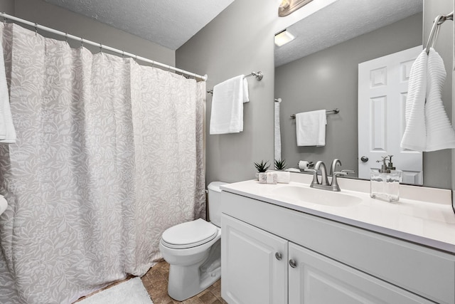 bathroom with vanity, toilet, and a textured ceiling