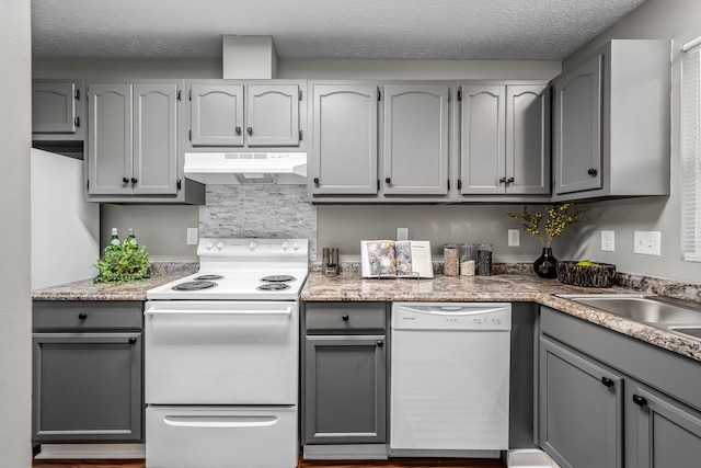 kitchen featuring backsplash, white appliances, a textured ceiling, and gray cabinetry