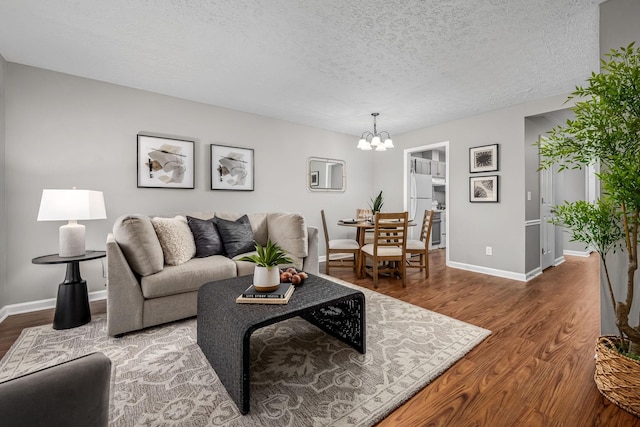 living room with an inviting chandelier, wood-type flooring, and a textured ceiling