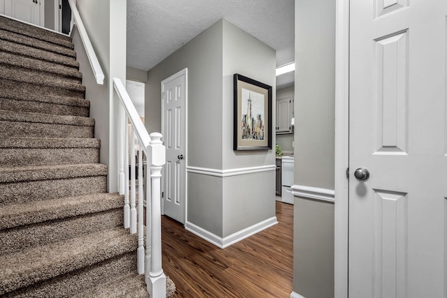 stairway with wood-type flooring and a textured ceiling