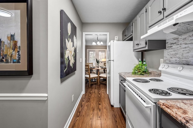 kitchen with dark hardwood / wood-style floors, gray cabinetry, white appliances, a notable chandelier, and a textured ceiling