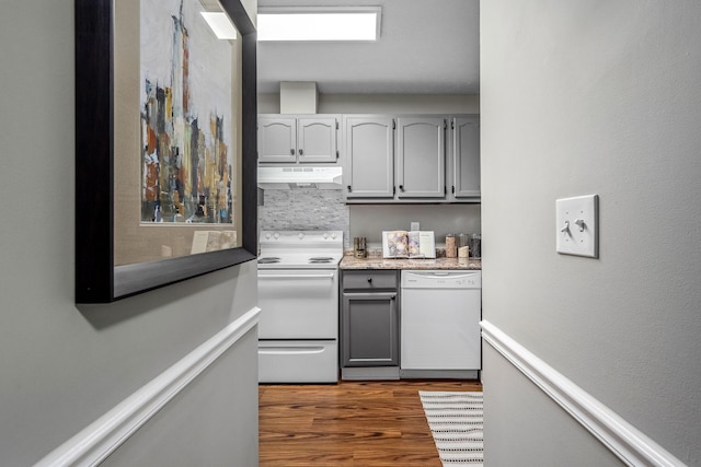 kitchen featuring white appliances, dark hardwood / wood-style flooring, gray cabinets, and decorative backsplash