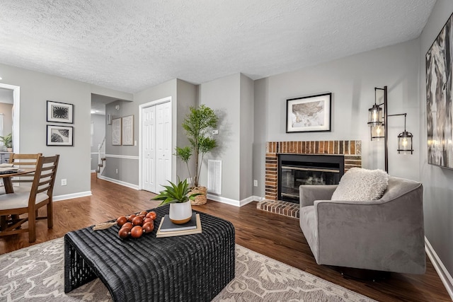 living room featuring a brick fireplace, hardwood / wood-style flooring, and a textured ceiling