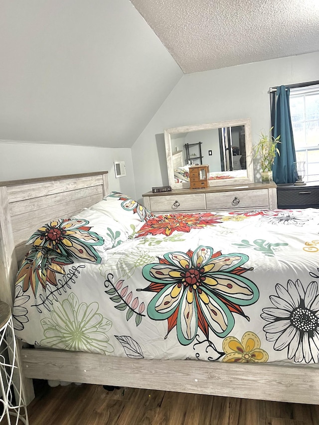 bedroom with vaulted ceiling, wood-type flooring, and a textured ceiling