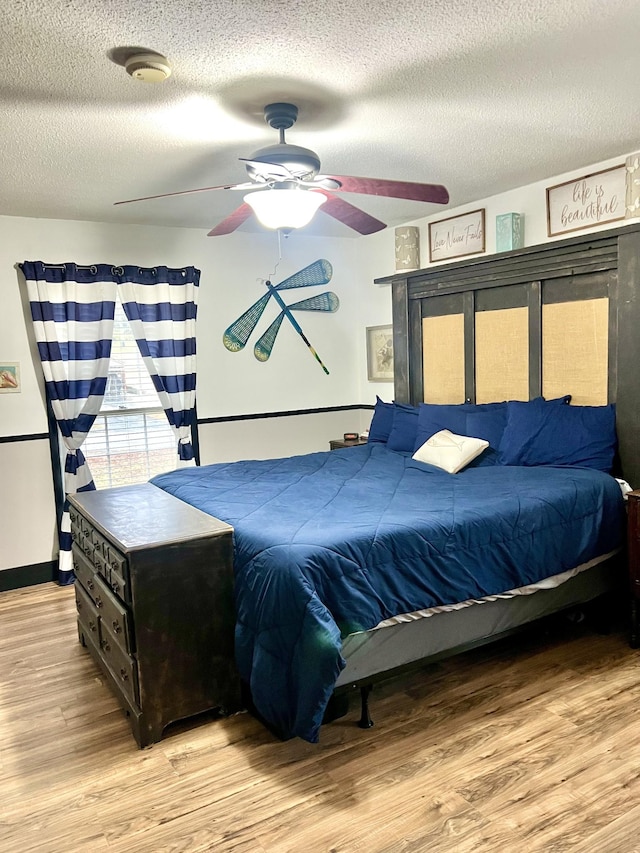 bedroom with ceiling fan, a textured ceiling, and light hardwood / wood-style floors