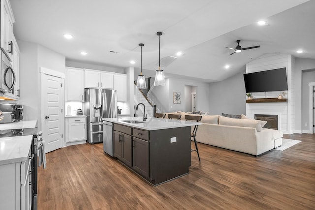 kitchen featuring sink, decorative light fixtures, stainless steel appliances, a kitchen island with sink, and white cabinets