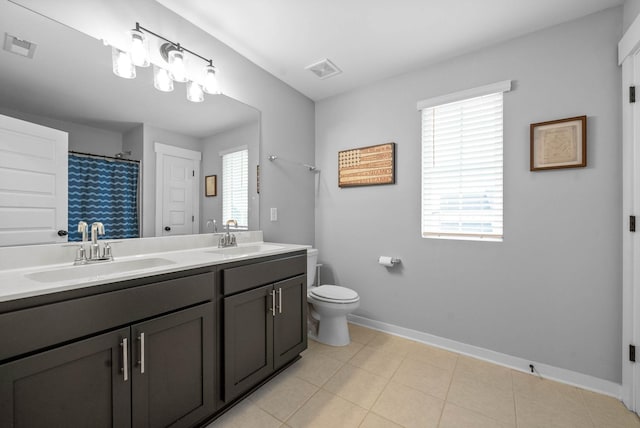 bathroom featuring vanity, tile patterned flooring, a wealth of natural light, and toilet