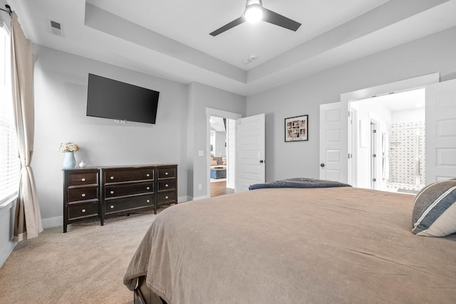 bedroom with light colored carpet, ceiling fan, and a tray ceiling