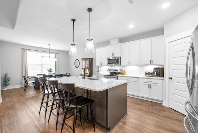 kitchen with white cabinetry, appliances with stainless steel finishes, sink, and decorative light fixtures